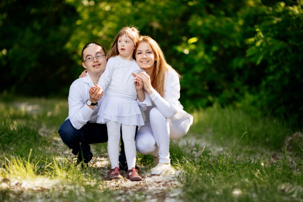 A devoted mom of special needs walks in nature with her husband and young daughter with Down syndrome, reinforcing inclusion, emotional bonding, and the positive impact of outdoor activities for children on the autism spectrum or with intellectual disabilities.

