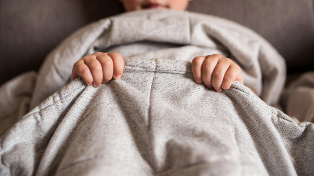 Close-up of a child holding the edge of a weighted blanket showing the sensory comfort it provides for kids with autism