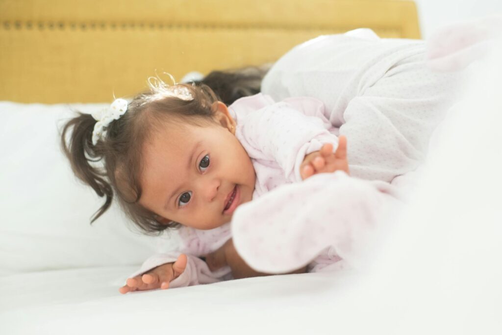 Baby girl with Down syndrome waking up restlessly in bed, illustrating the sleep disruptions and nighttime challenges common in autism and developmental disabilities