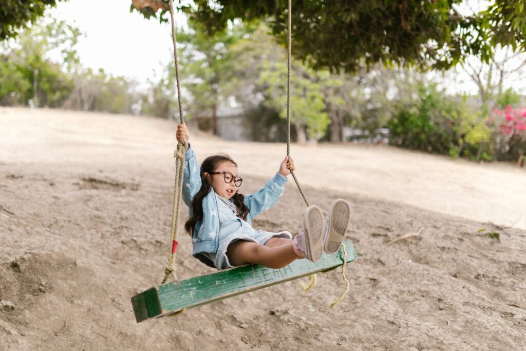 Young girl swinging on an outdoor rope swing, illustrating vestibular input and how swinging calms the nervous system in autism