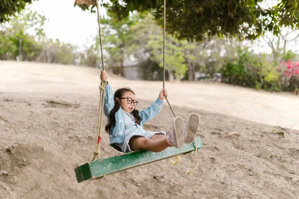 Young girl swinging on an outdoor rope swing, illustrating vestibular input and how swinging calms the nervous system in autism