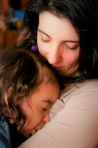exhausted mom kneeling beside her autistic child during an autism meltdown vs tantrum moment