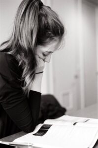 Tired mom writing notes to prepare for talking to school about sensory needs with autism scripts