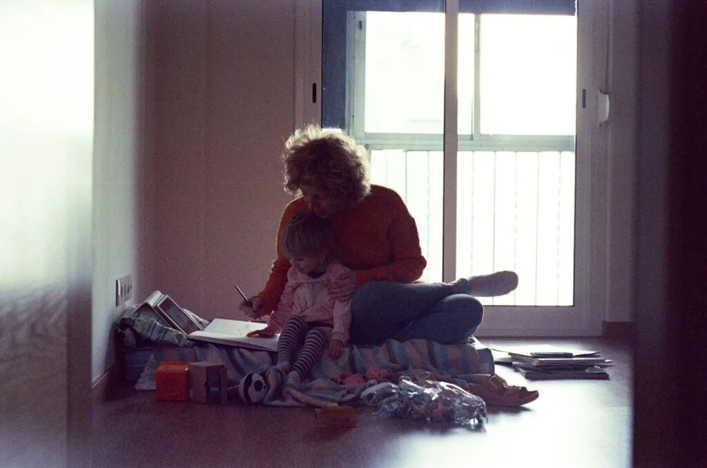 autism self-injurious behavior head banging - exhausted mother sitting on floor comforting autistic child