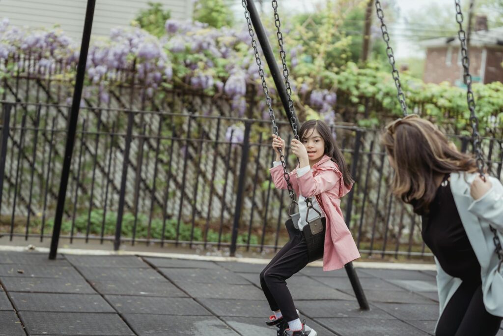 Girl with Down syndrome enjoying a sensory swing at a playground, showing vestibular input and movement therapy for autism