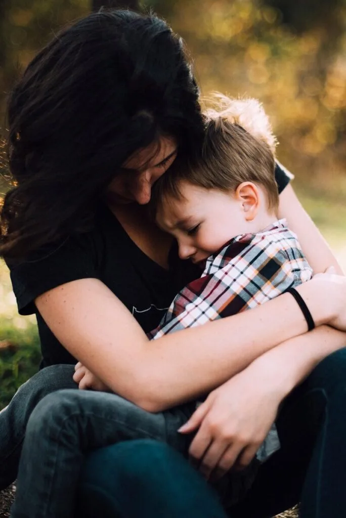 autism chronic pain connection - mother comforting child with pain hugging on lap