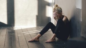 Exhausted mother sitting on hallway floor during her autistic child's bedtime meltdown late at night