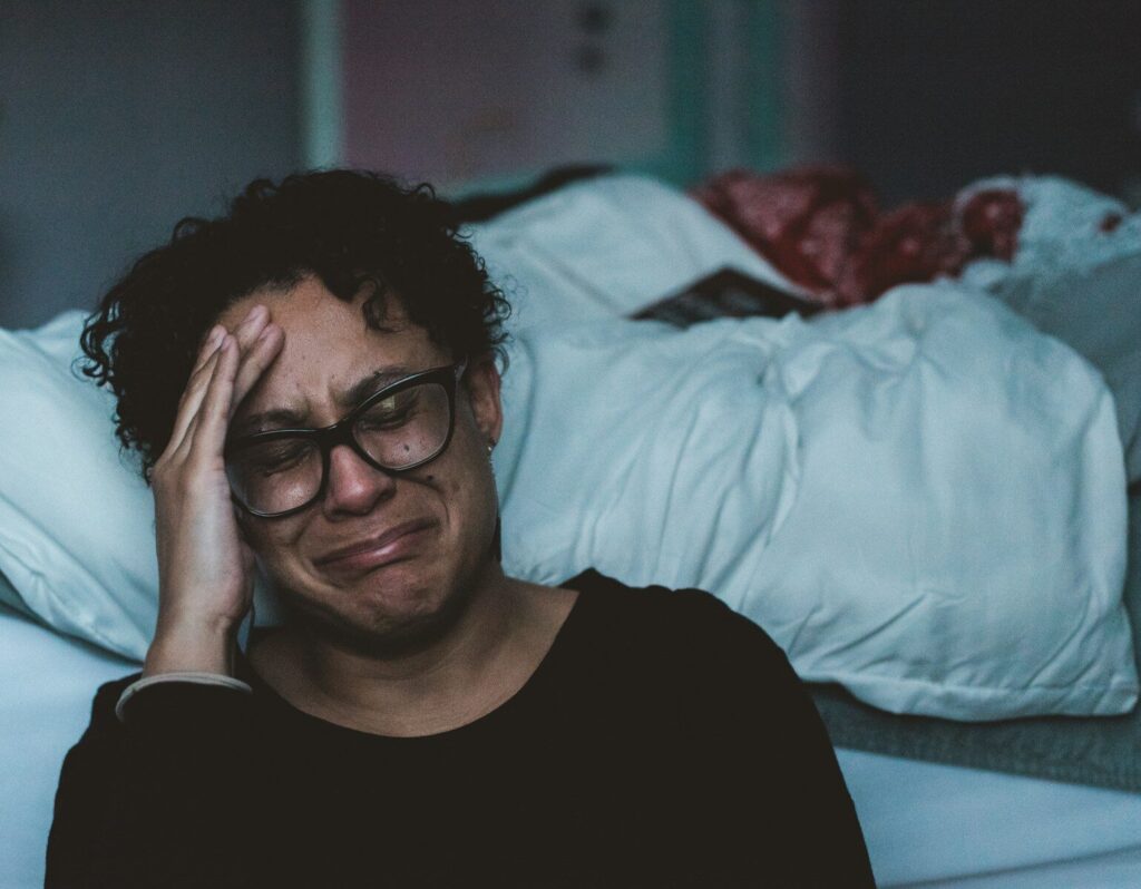 Exhausted special needs mom in need of respite care sitting alone on the edge of a bed