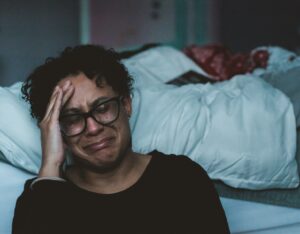 Exhausted special needs mom in need of respite care sitting alone on the edge of a bed