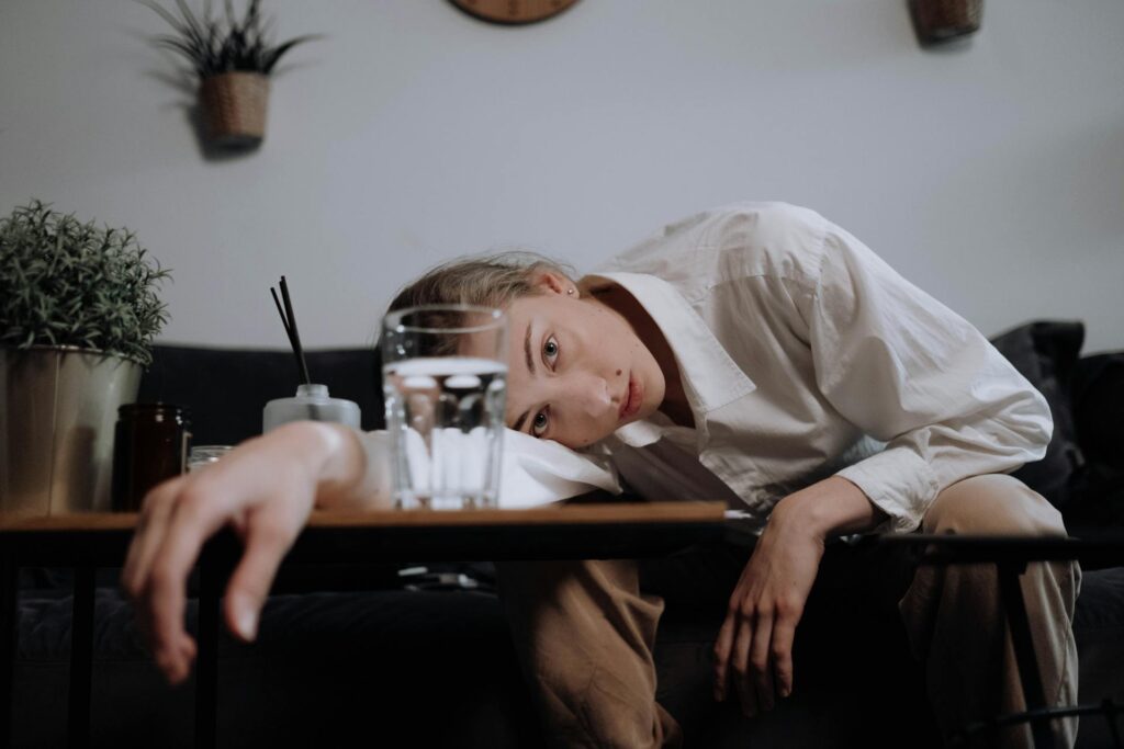 Woman slumped forward with her head resting on her arms at a table, depicting the real fatigue and exhaustion of special needs mom burnout — not laziness