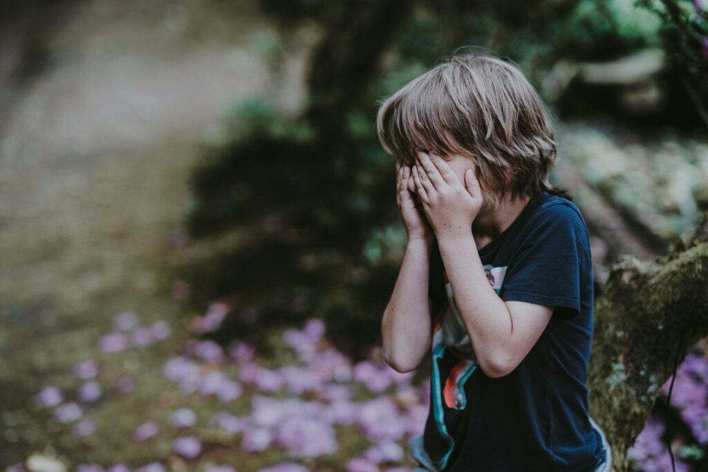 child covering face showing autism masking behavior and suppressed emotions