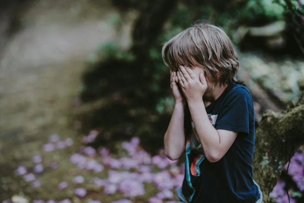 child covering face showing autism masking behavior and suppressed emotions