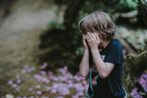 child covering face showing autism masking behavior and suppressed emotions
